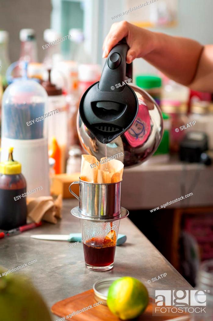Stock Photo: The process of making Thai lemon tea. Woman right hand pouring hot water into dripper above tea glass.