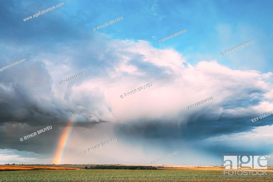 Stock Photo: Dramatic Sky During Rain With Rainbow On Horizon Above Rural Landscape Field. Agricultural And Weather Forecast Concept. Countryside Meadow In Autumn Rainy Day.