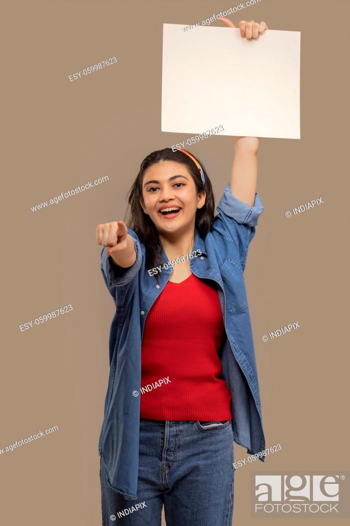 Stock Photo: Portrait of a young woman holding white sheet pointing elsewhere with her forefinger.