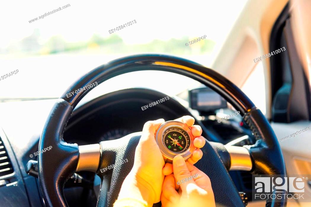Stock Photo: Asian woman inside a car and using compass to navigate while driving the car she find navigation location to go, Transportation and vehicle concept.