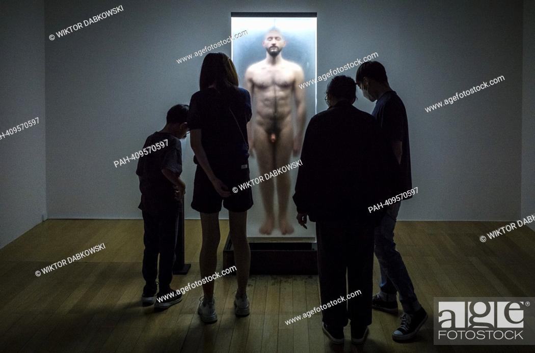 Photo de stock: People look at sculpture of a naked man enclosed in a glass display case during the SUPERNATURAL: Sculptural Visions of the Body exhibition in Taipei.