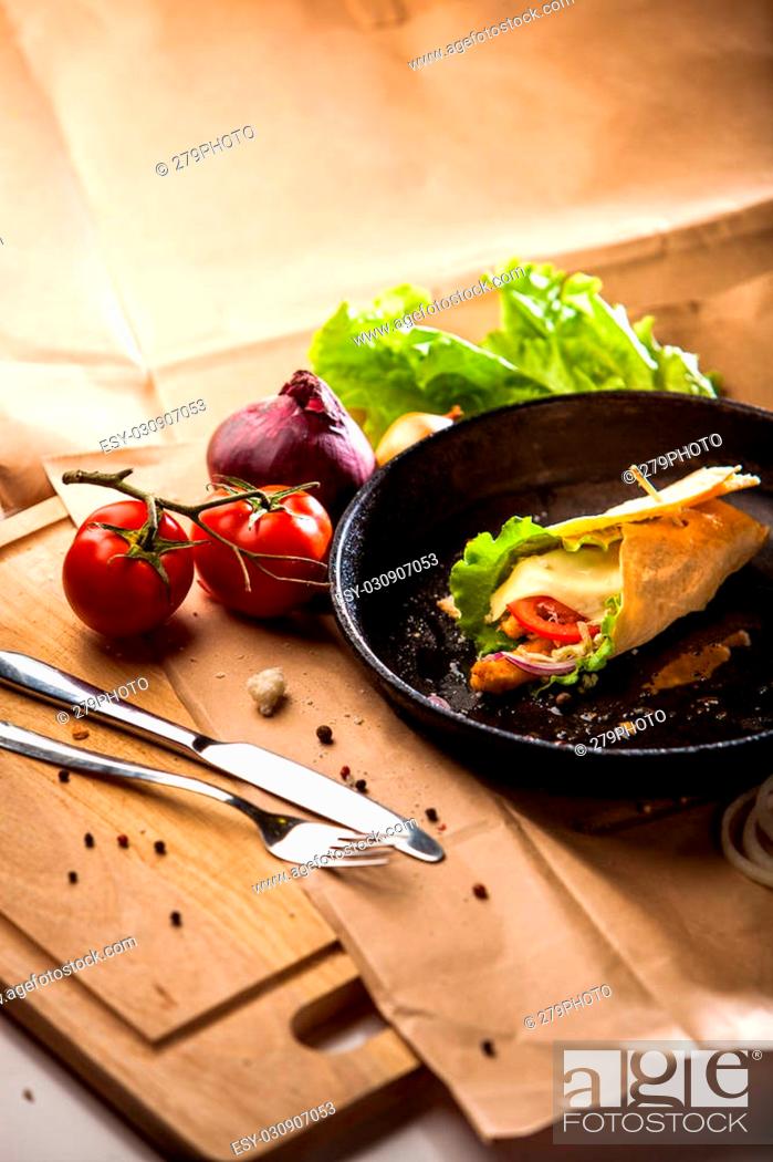 Stock Photo: Home baked hot roll with chicken, cheese, onion, tomato on a cast-iron pan on wodden board close up.