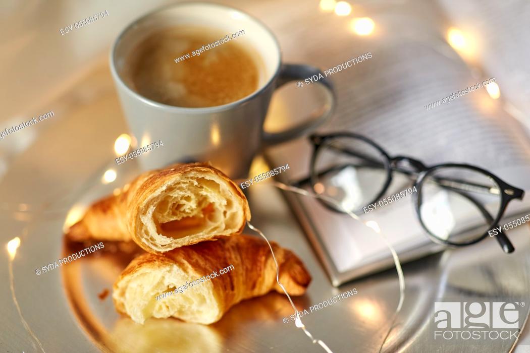 Stock Photo: croissants, cup of coffee, book and glasses in bed.