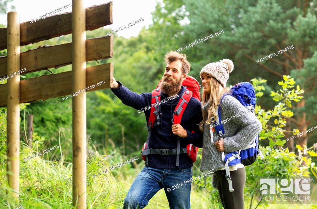 Stock Photo: couple of travelers with backpacks at signpost.