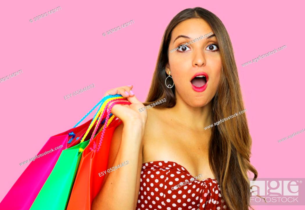 Stock Photo: Portrait of a pretty shocked fashion girl holding shopping bags isolated over pink background.