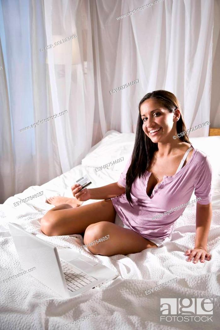 Stock Photo: Hispanic woman laying in bed shopping on internet.
