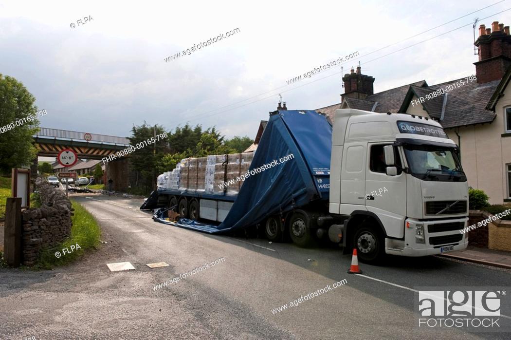 Stock Photo: Articulated lorry passing under low railway bridge has roof of trailer ripped off, Kirkby Stephen, Cumbria, England.