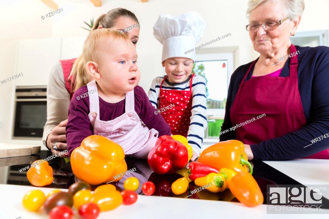 Stock Photo: Mother, grandmother and children happily preparing meal in kitchen.