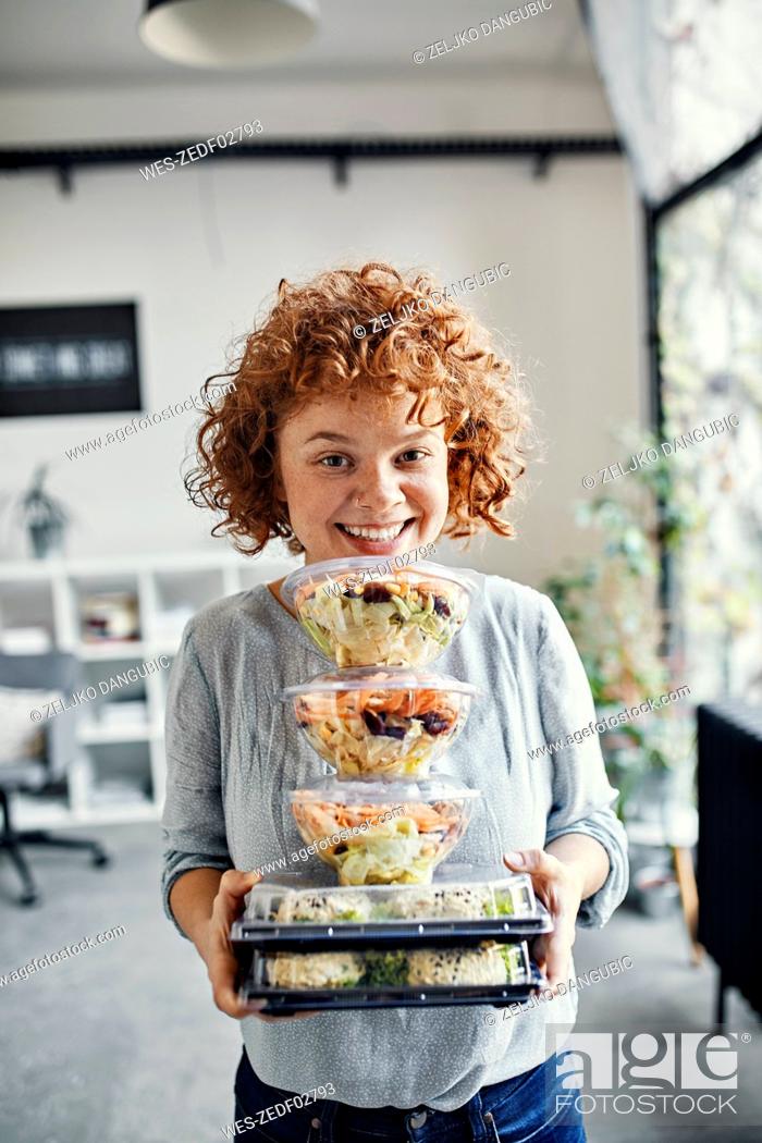 Stock Photo: Portrait of smiling businesswoman holding stack of takeaway food in office.