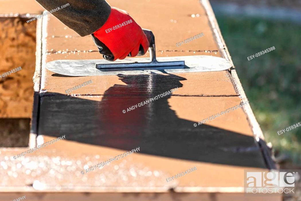 Stock Photo: Construction Worker Using Trowel On Wet Cement Forming Coping Around New Pool.