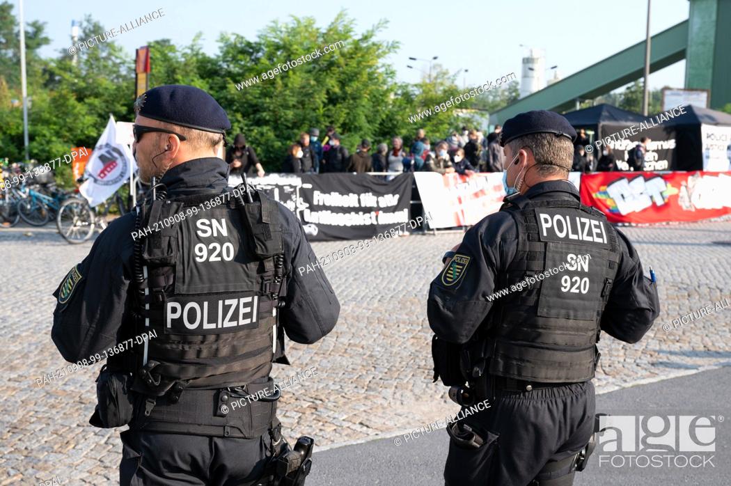 Stock Photo: 08 September 2021, Saxony, Dresden: Police officers stand in front of demonstrators before the start of a trial against a woman and three men at the Dresden.