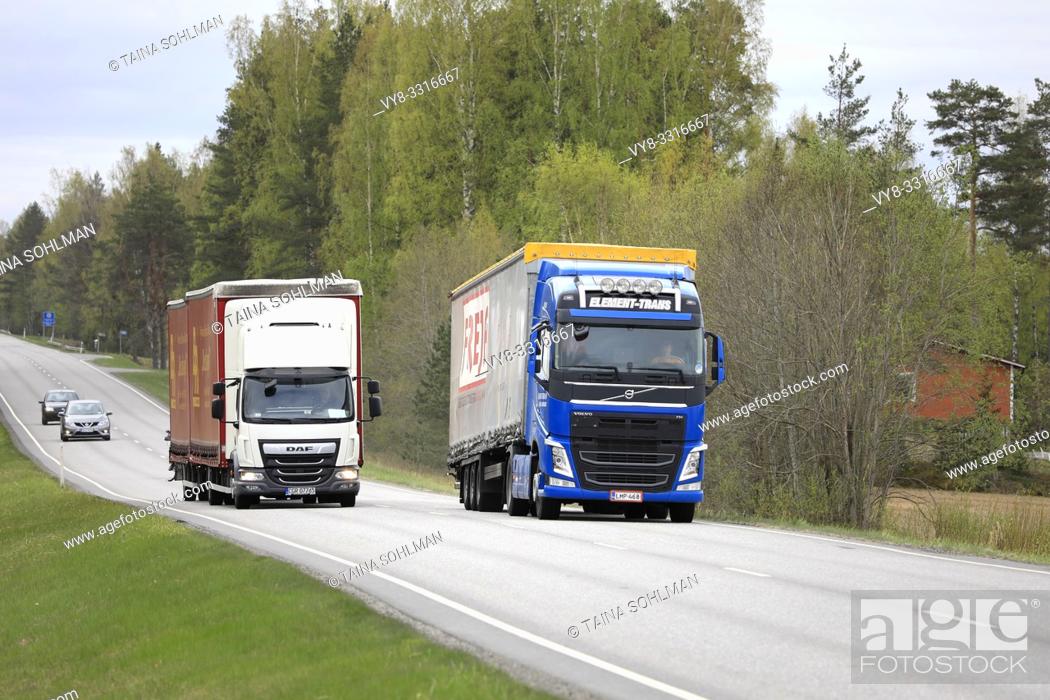 Stock Photo: Salo, Finland - May 10, 2019: Blue Volvo FH truck in front of semi trailer overtakes truck pulling full trailer on rural highway in South of Finland.