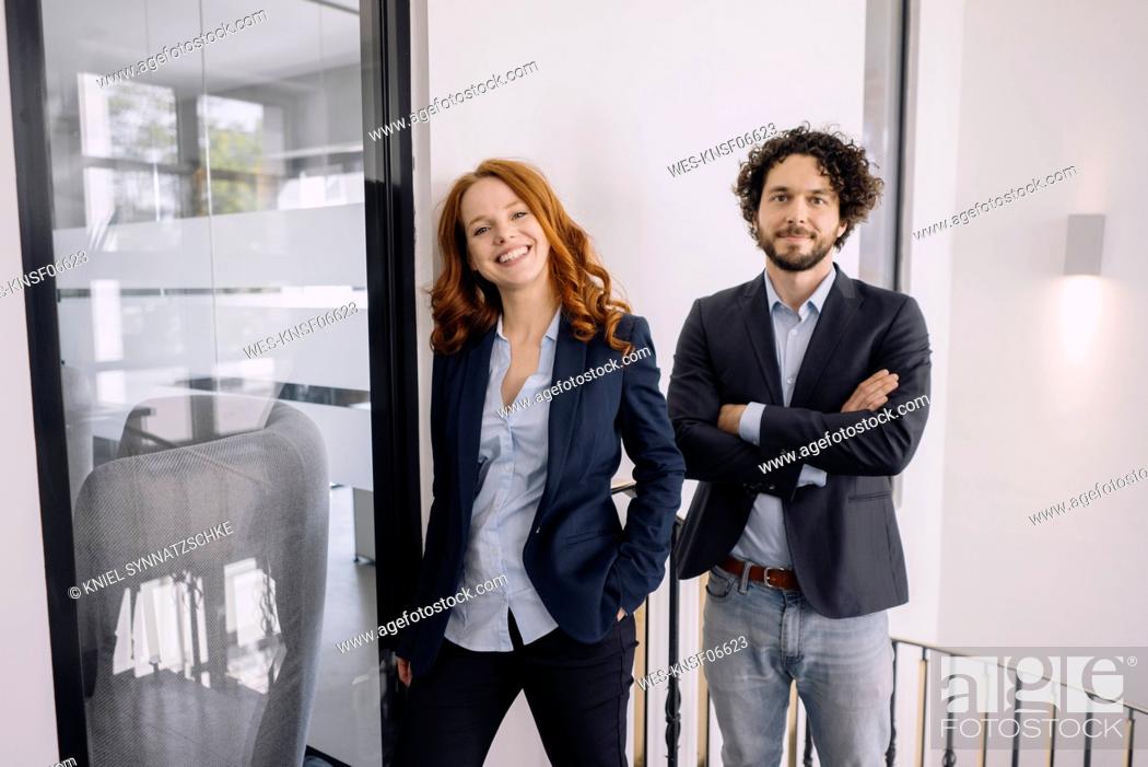 Stock Photo: Portrait of confident businessman and businesswoman in office.