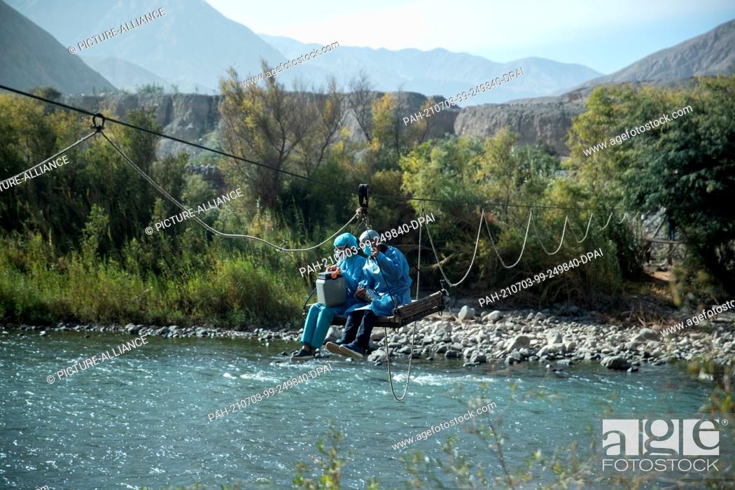 Stock Photo: 03 July 2021, Peru, Arequipa: Peruvian health workers cross a river by cable car to reach a remote village. There they are supposed to vaccinate the people.