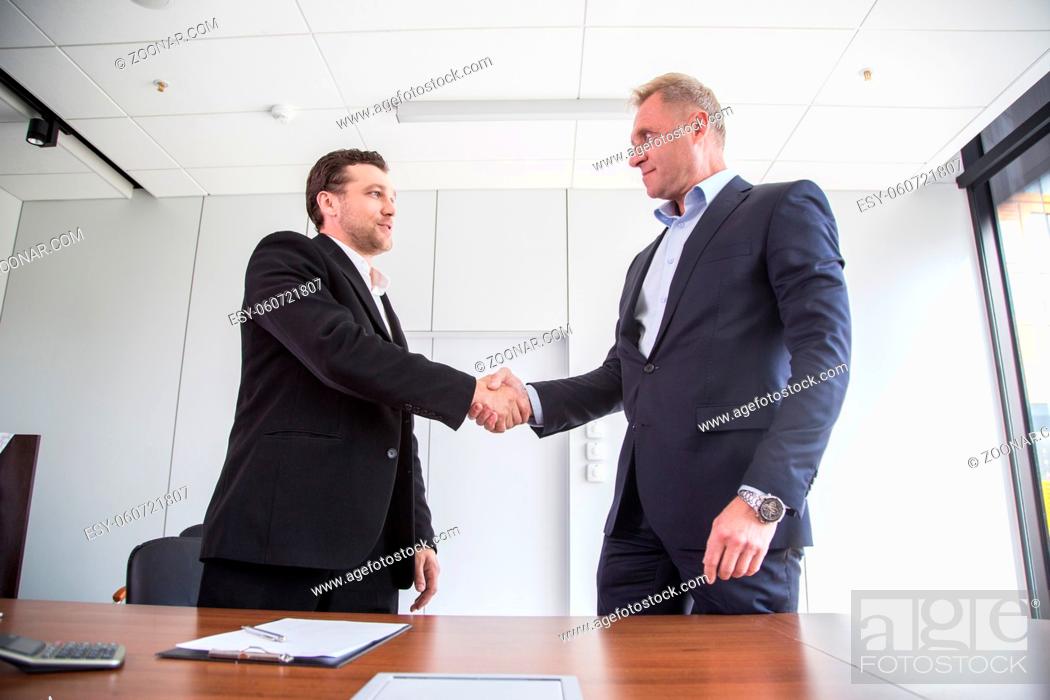 Stock Photo: Business people in formal wear sign contract and shaking hands.