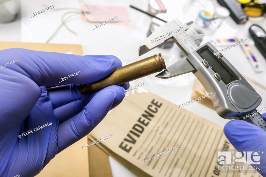Stock Photo: Expert Police measures bullet caliber in ballistic lab, conceptual image.