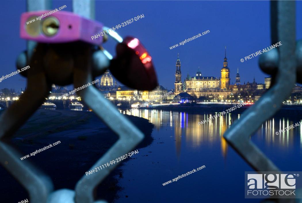 Stock Photo: 16 November 2021, Saxony, Dresden: Castles hang on the railing of the Marienbrücke in front of the old town on the Elbe with the Frauenkirche (l-r).