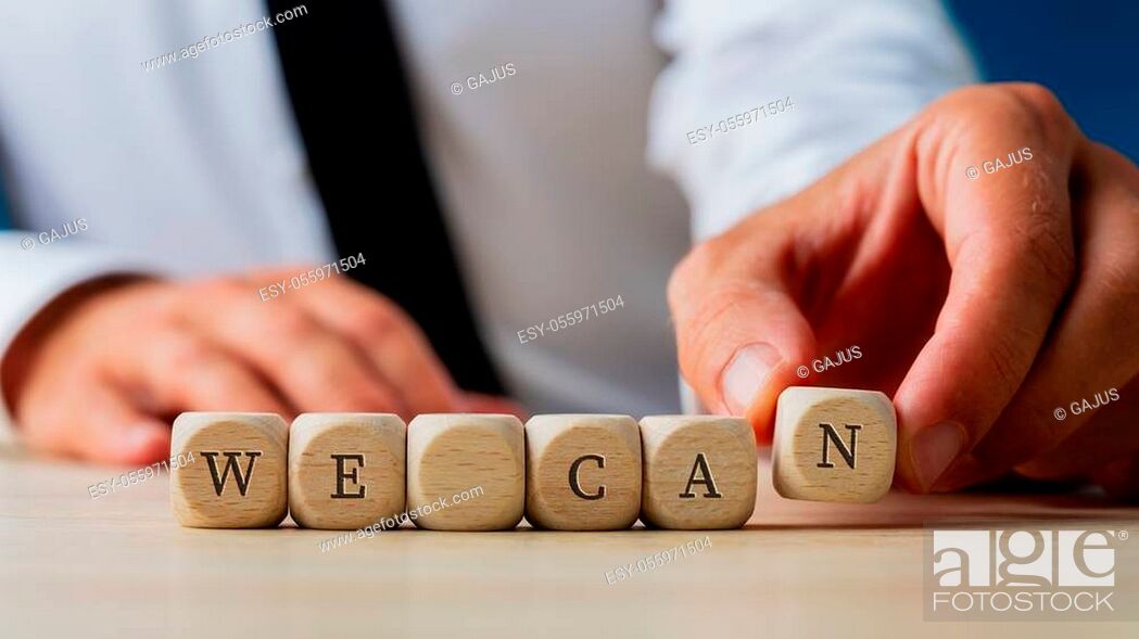 Stock Photo: Businessman assembling a We can sign spelled on wooden dices in a conceptual image.