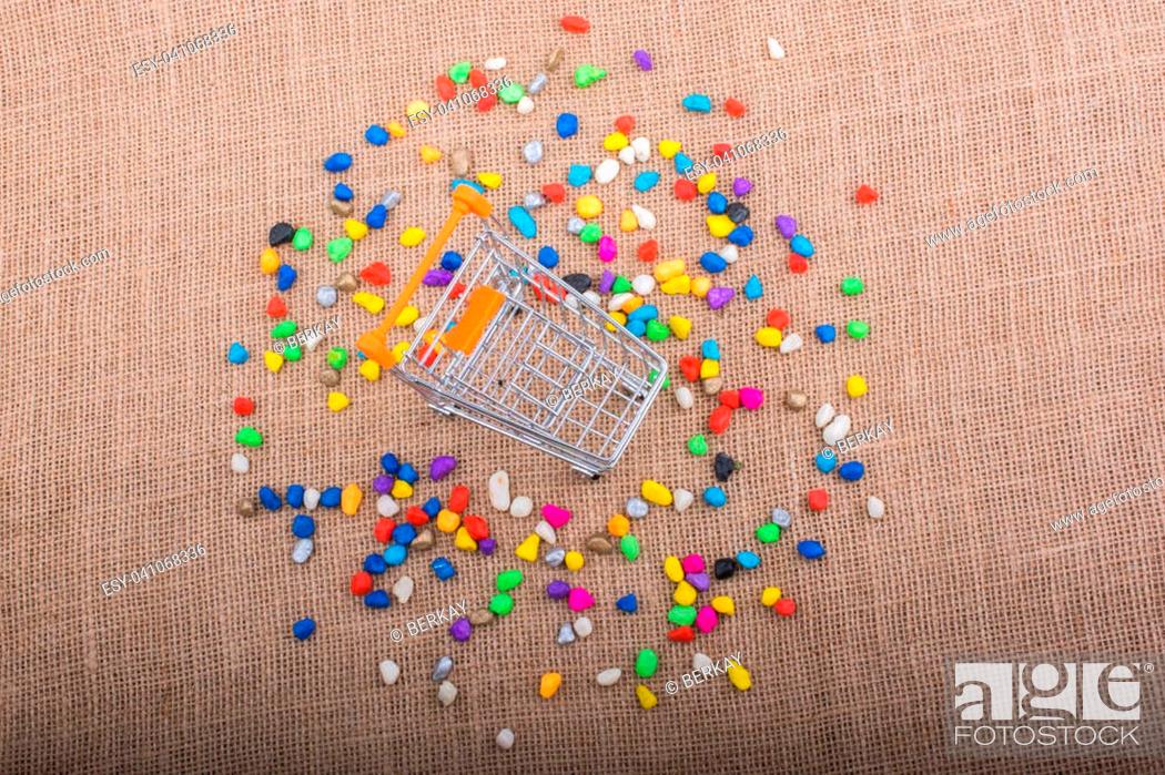 Stock Photo: Little trolley amid Colorful pebbles on canvas background.