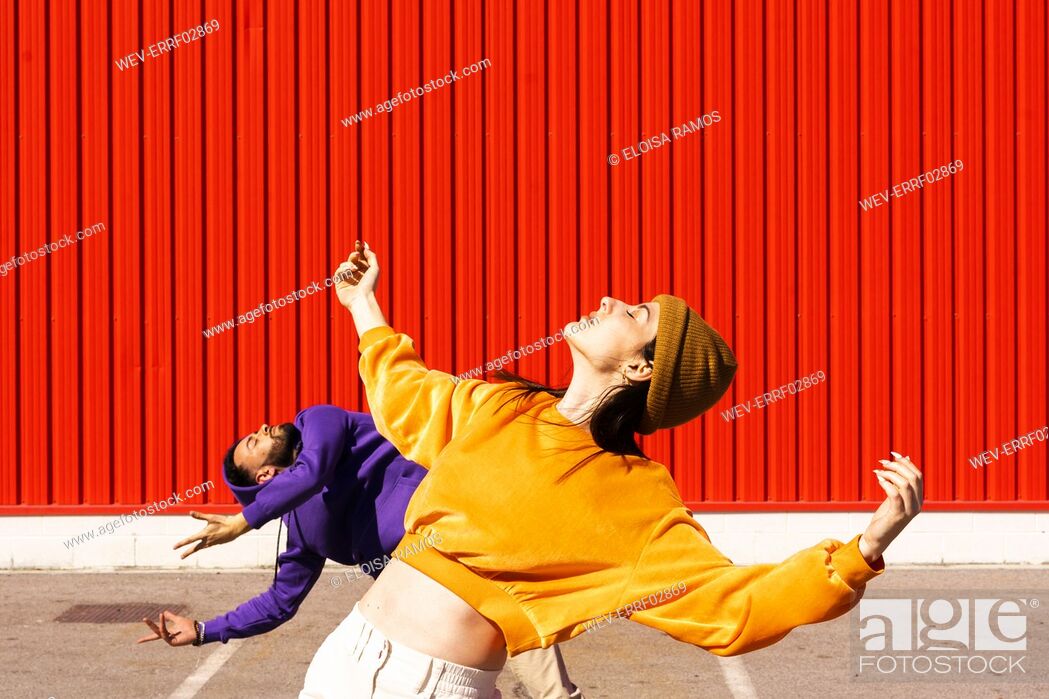 Stock Photo: Young man and woman performing in front of a red wall.