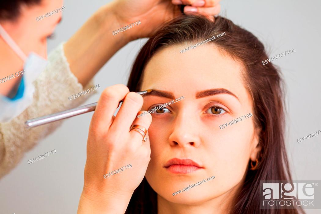 Photo de stock: Master makeup corrects and gives shape to eyebrows in a beauty salon. Professional care for face.