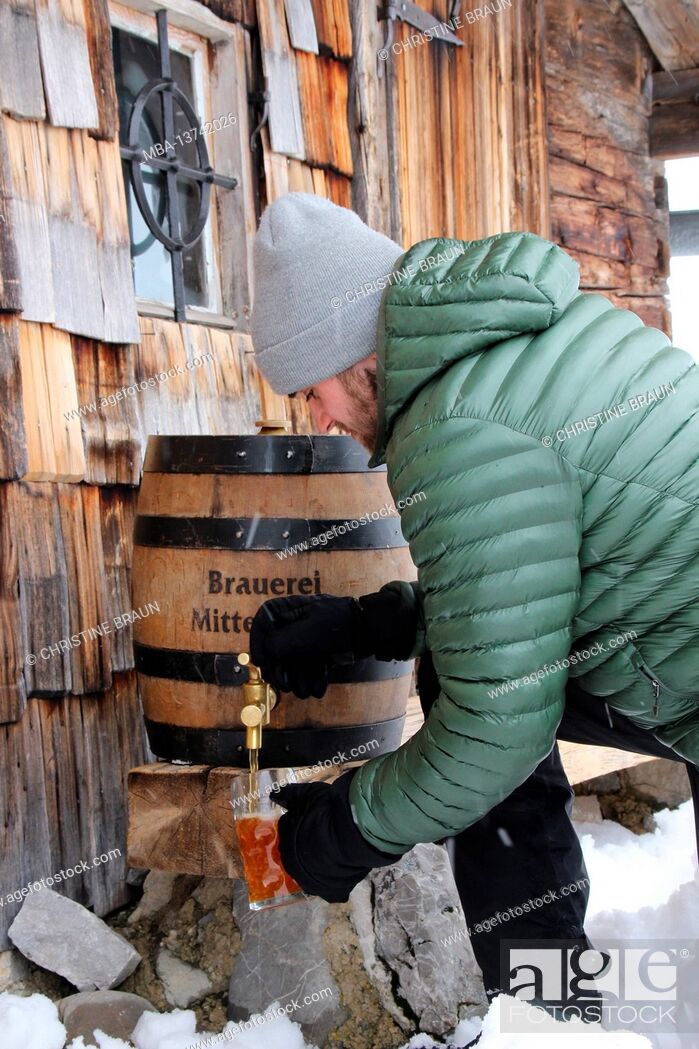 Stock Photo: Young man pouring beer, beer barrel, Mittenwald brewery, mountain hut, winter, atmospheric.