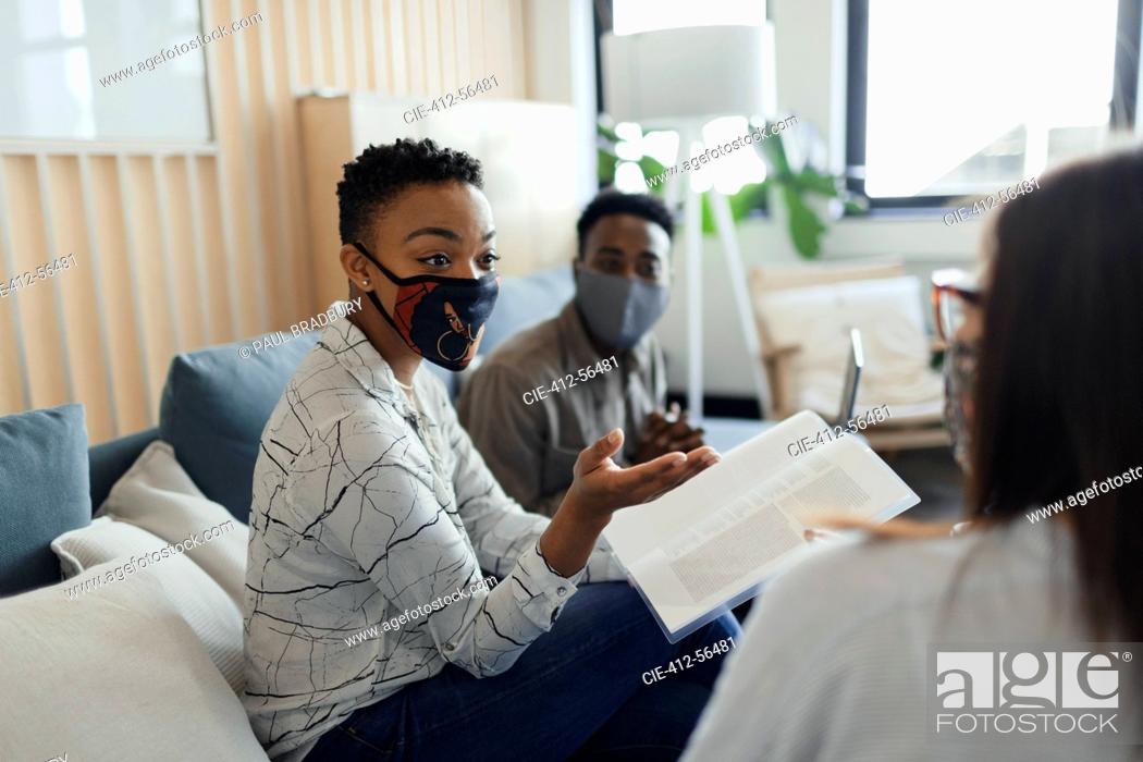 Stock Photo: Business people in face masks discussing paperwork in office meeting.