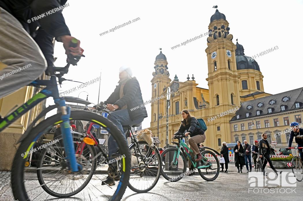 Stock Photo: Theme picture winter in the coronavirus pandemic. Hard lockdown. Cyclists and pedestrians on Odeonsplatz in Muenchen with Theatiner Church on February 19th.