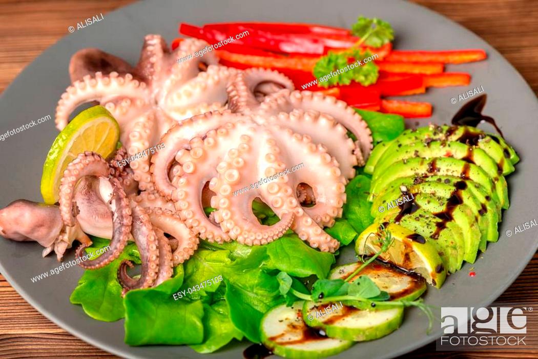 Stock Photo: octopus served with sliced avocado, lettuce, red pepper and lime on plate, natural seafood, ethnic cuisine.