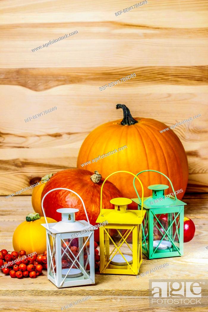 Stock Photo: Colorful lanterns and orange pumpkins on wooden background.