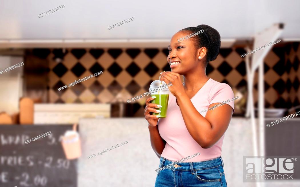 Stock Photo: happy african american woman drinking green juice.