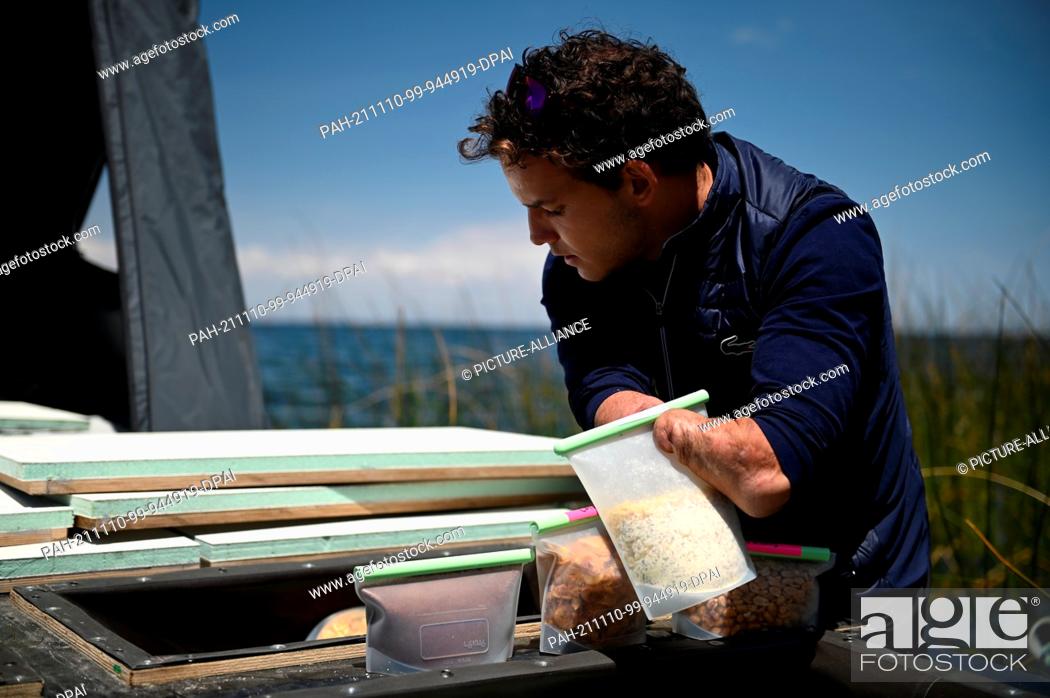 Stock Photo: 10 November 2021, Bolivia, Copacabana: Theo Curin, Paralympic swimmer from France, is piling food into an eco-boat that will accompany him as he crosses Lake.