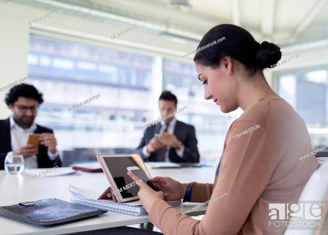 Stock Photo: Businesswoman using smart phone in conference room meeting.