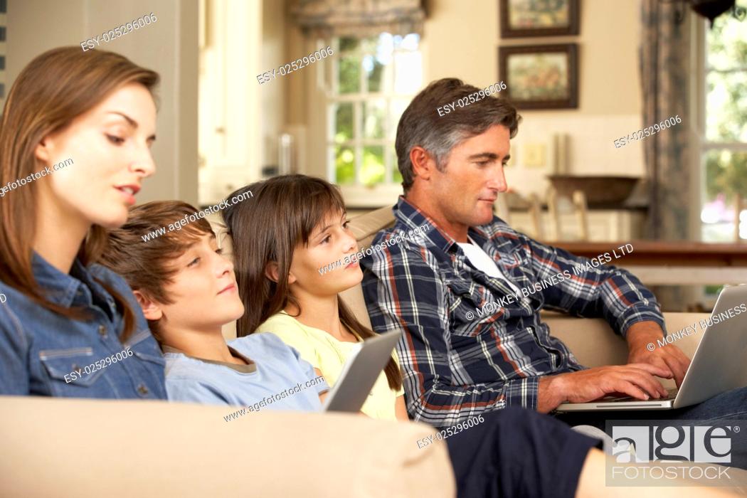 Imagen: Children Watching TV Whilst Parents Use Laptop And Tablet Computer At Home.