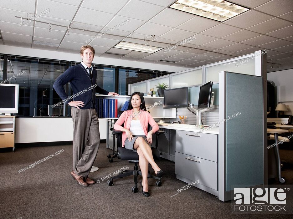 Stock Photo: Caucasian businessman and Asian businesswoman team of people in a cubicle office space.