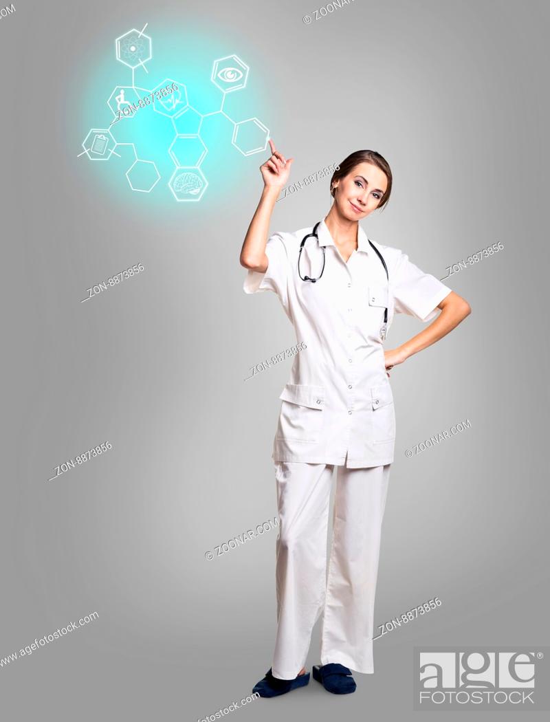 Stock Photo: Young female doctor in uniform touch hexagon with icons over gray background.