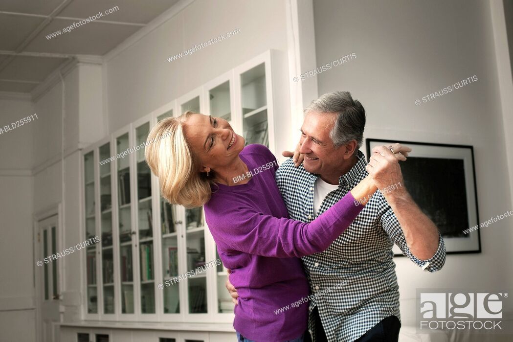Stock Photo: Smiling Caucasian couple dancing in home.