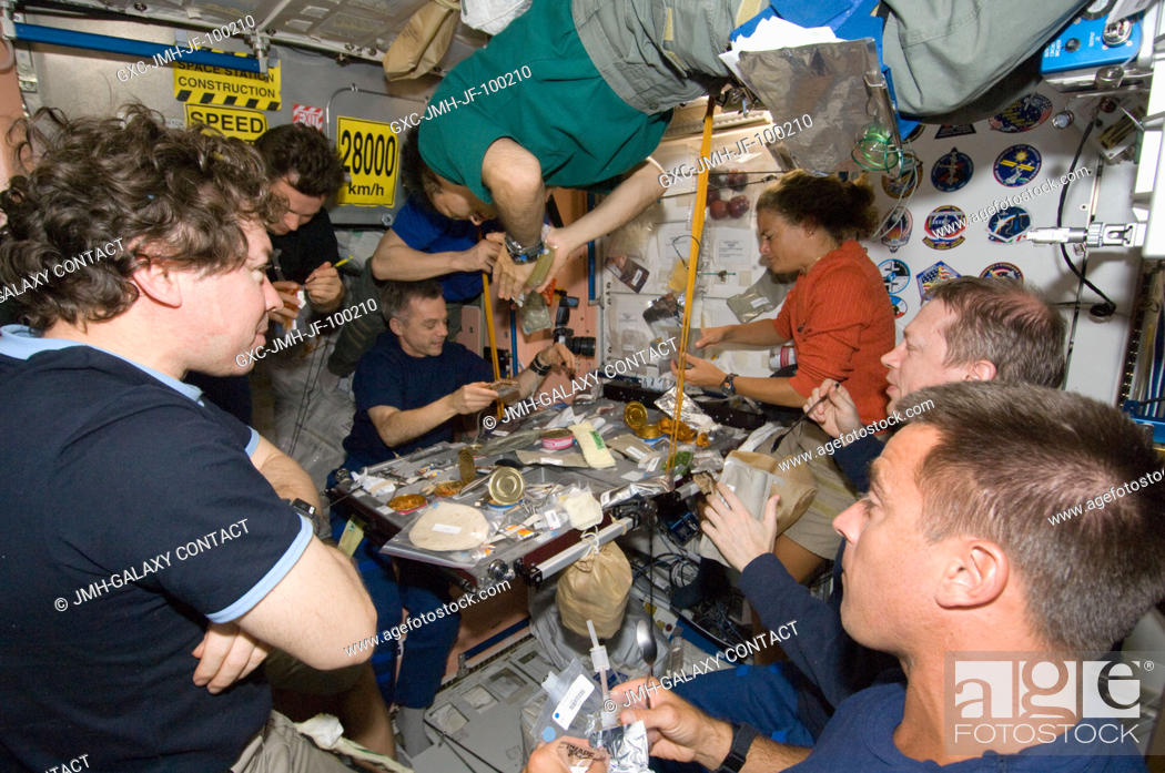 Stock Photo: Eight of a total aggregation of 13 astronauts and cosmonauts are pictured at meal time aboard the International Space Station.