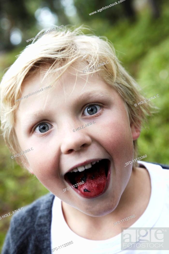 Stock Photo: A boy sticking out his tongue which has been coloured with blueberries.