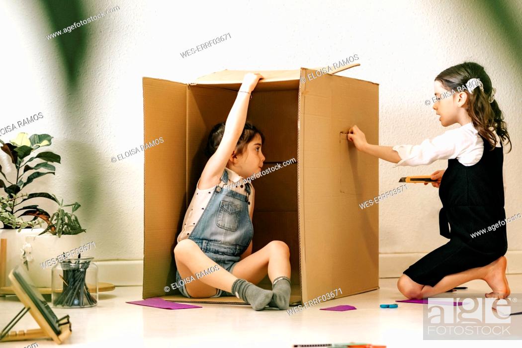 Stock Photo: Two little sisters building house with cardboard box.