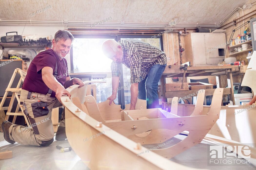 Stock Photo: Male carpenters making wood boat in workshop.