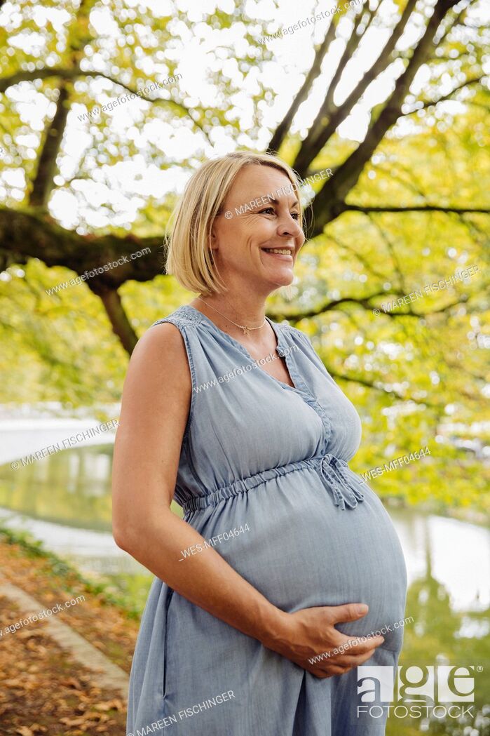 Stock Photo: Happy mature pregnant woman standing in park.