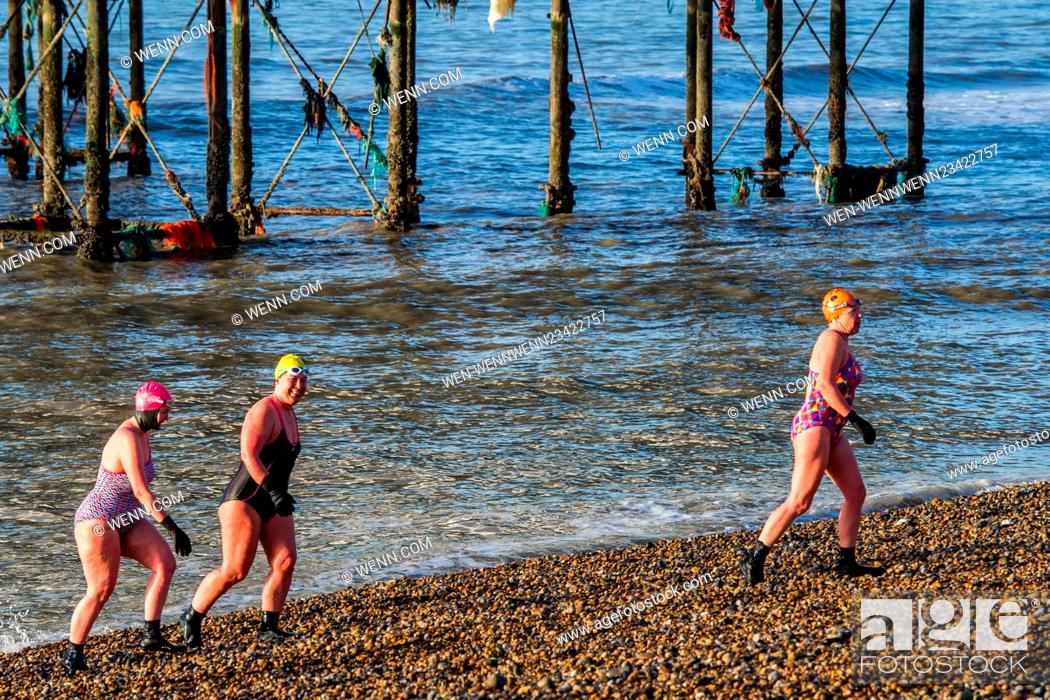 Stock Photo: As the sun rises over Brighton Beach, three ladies go for a cold dip in the ocean on what is set to be a very sunny day. Featuring: View.