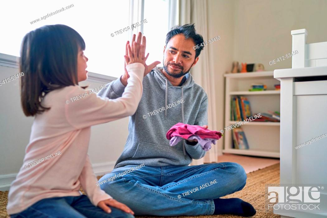 Stock Photo: Father and daughter folding laundry and high fiving.