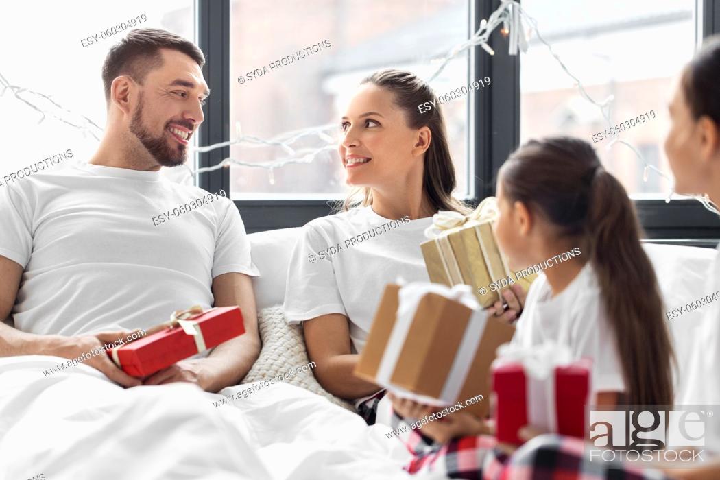 Stock Photo: happy family with christmas gifts in bed at home.