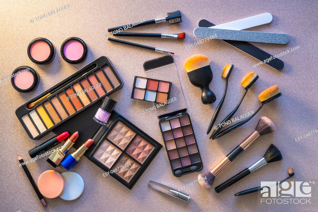 Stock Photo: Cosmetics makeup lipstick eye shadows arrangement on glitter silver table.