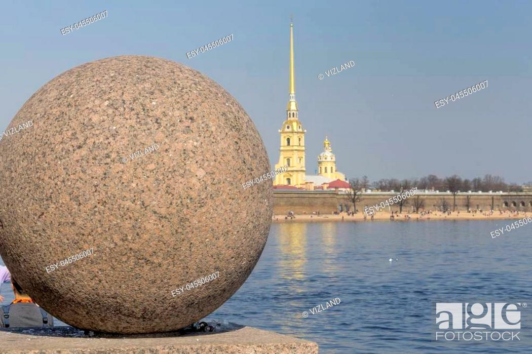 Stock Photo: A large granite ball on the Spit of Vasilievsky Island against the background of the Peter and Paul Fortress and the Neva River.
