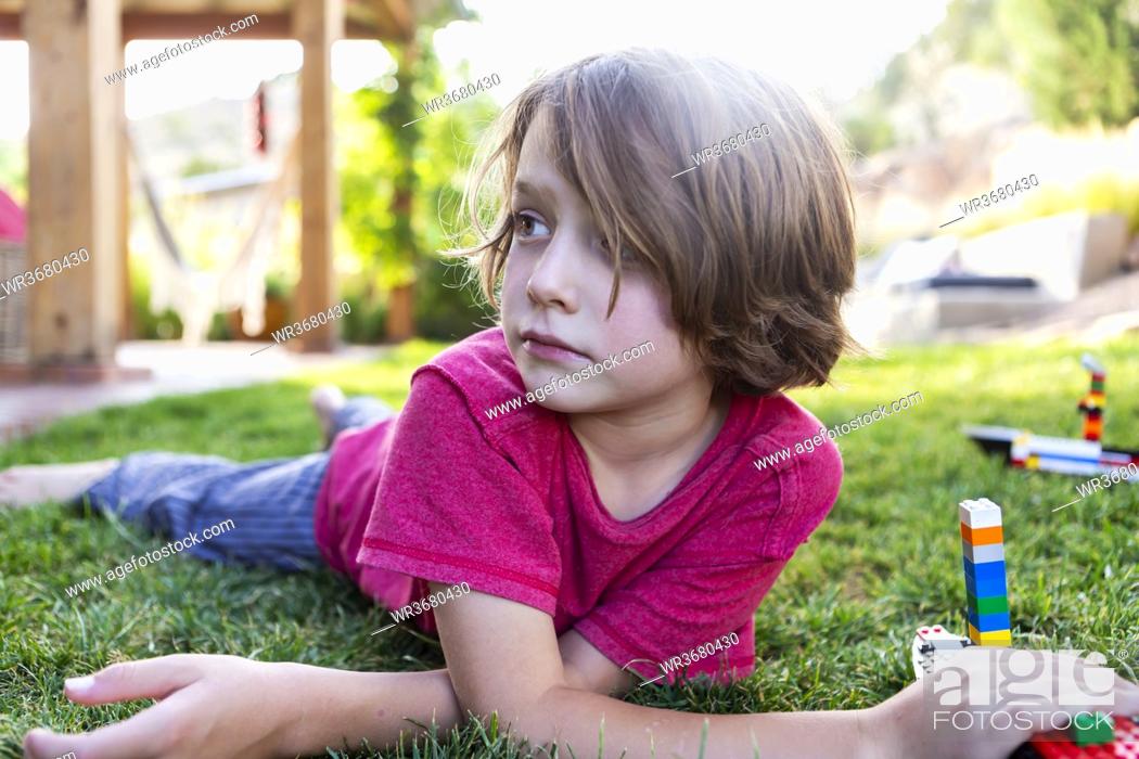 Boy with brown hair lying on lawn, playing with building blocks, Stock  Photo, Picture And Royalty Free Image. Pic. WR3680430 | agefotostock