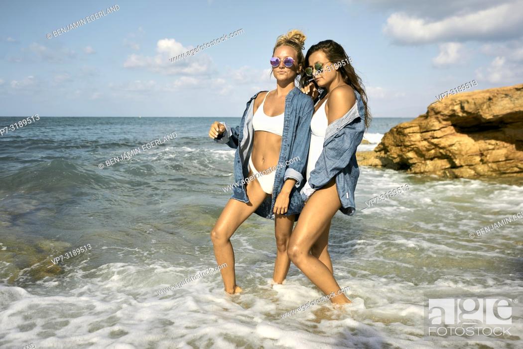 Stock Photo: Two women standing in water at beach, Chersonissos, Crete, Greece.