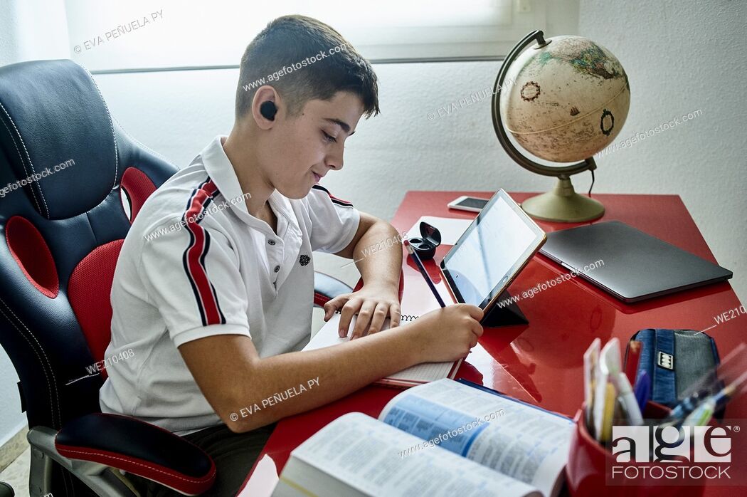 Stock Photo: teenager teaching online classes and doing his homework in his study room.